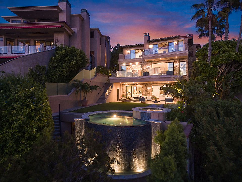 Two Emerald Bay at twilight, viewed from the rear gardens with the pool illuminated and the Pacific sky glowing